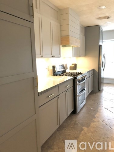 A kitchen with white cabinets and a tiled floor.