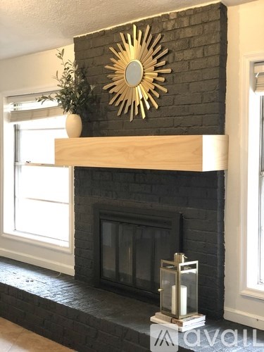 A black brick fireplace with a wooden mantle and a sunburst mirror above it.
