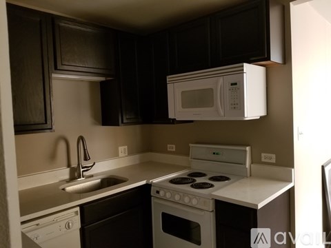 A kitchen with black cabinets and white appliances.