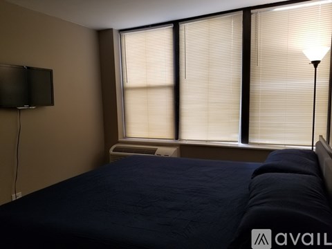 A bedroom with a bed, a television, and a window with blinds.