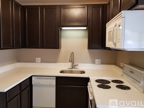 A kitchen with dark brown cabinets and white appliances.
