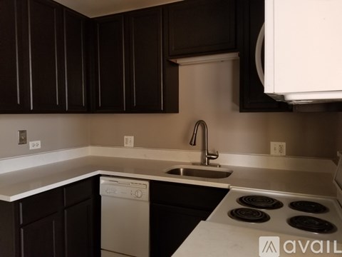 A kitchen with dark brown cabinets and a white dishwasher.