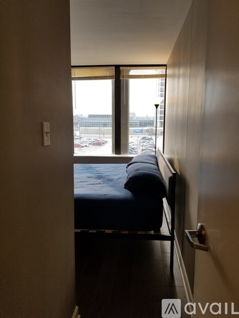 A bedroom with a bed and a window overlooking a parking lot.