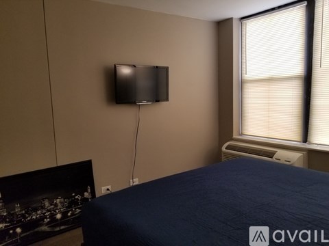 A bedroom with a bed, a television, and a window with blinds.