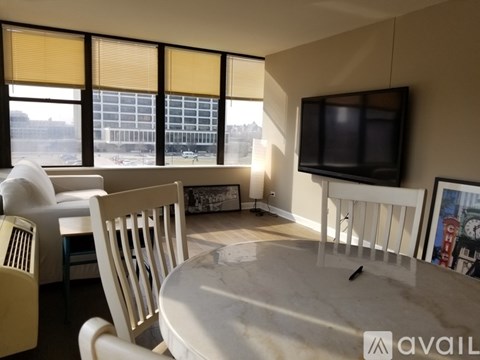 A living room with a television, a couch, a chair, and a table.