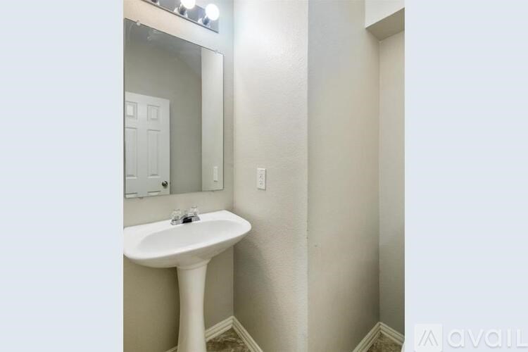 A white pedestal sink in a small bathroom.