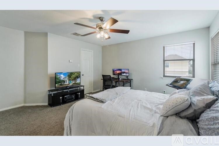 A bedroom with a bed, a television, and a ceiling fan.