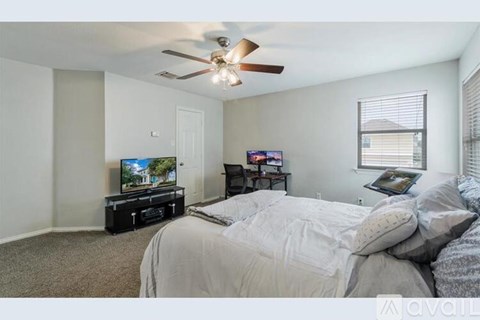 A bedroom with a bed, a television, and a ceiling fan.