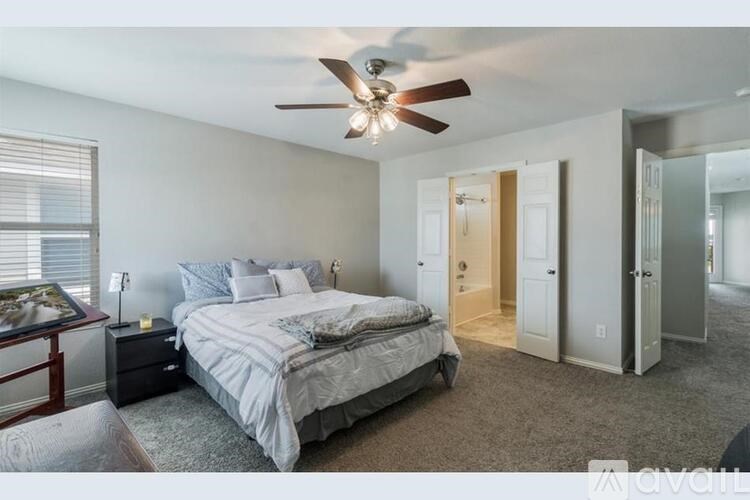 A bedroom with a bed, nightstand, and a ceiling fan.