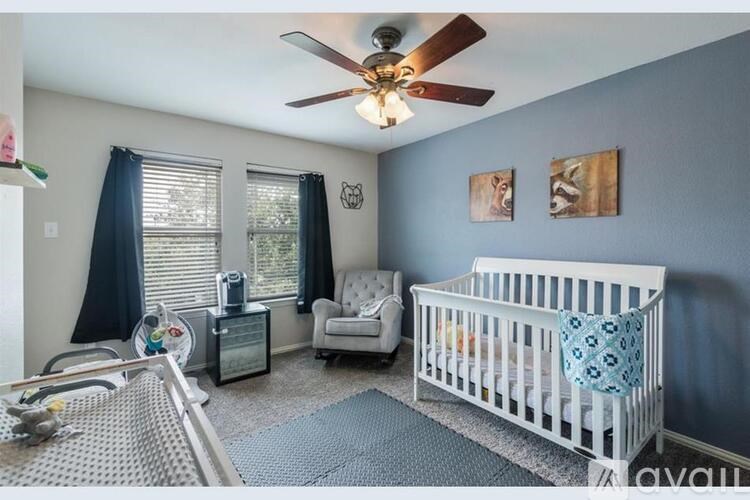 A baby's room with a white crib and a ceiling fan.