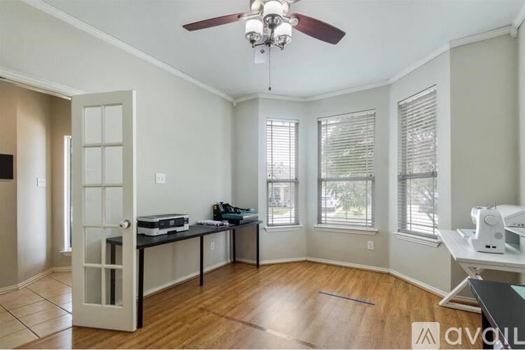 A room with a ceiling fan and a desk with a computer.