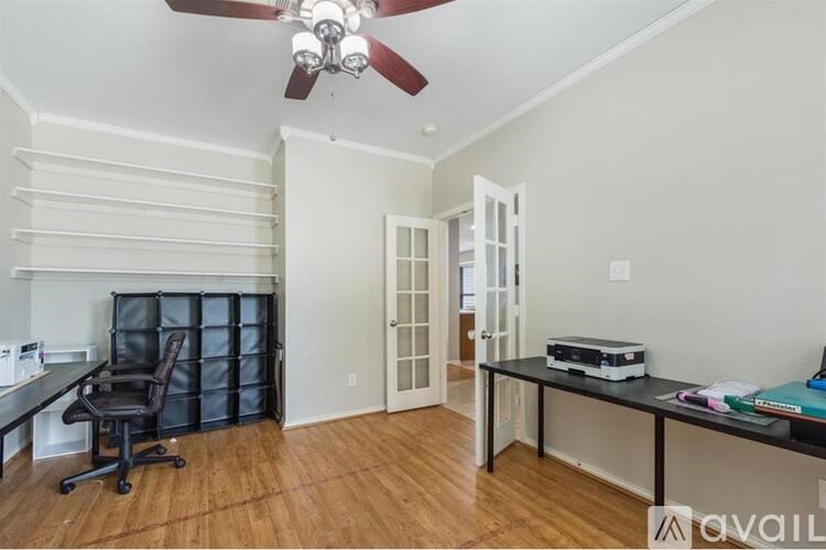 A room with a ceiling fan and a desk with a printer on it.