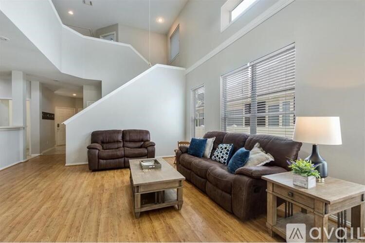 A living room with a brown couch and a wooden floor.