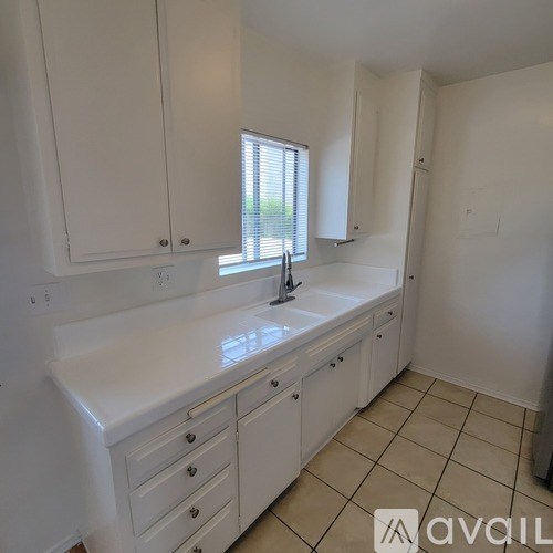 A kitchen with white cabinets and a sink.