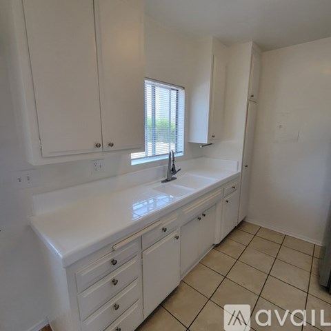 A kitchen with white cabinets and a sink.