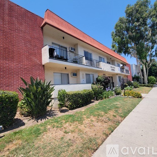 A red brick building with a balcony and a green lawn in front.