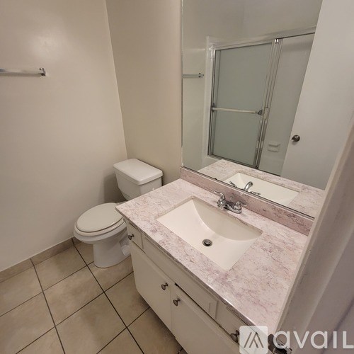 A bathroom with a toilet, sink, and mirror.