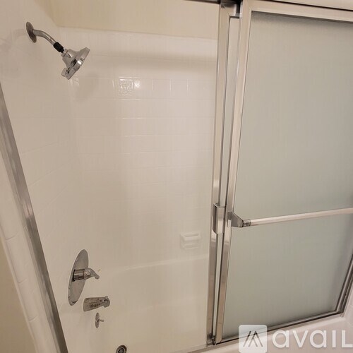 A shower with a glass door and a chrome handle.