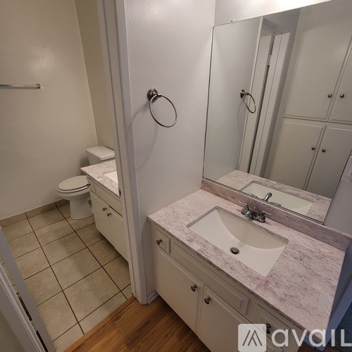 A bathroom with a toilet, sink, and mirror.