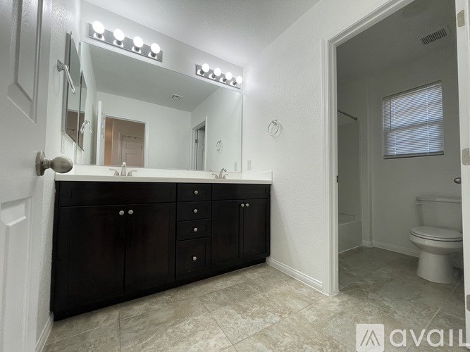 A bathroom with a vanity, mirror, and toilet.