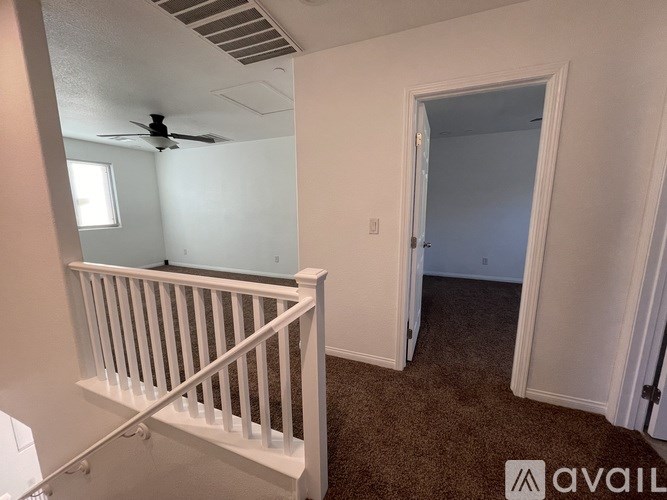 A room with a carpeted floor and a ceiling fan.