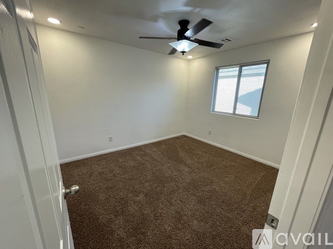 A room with a carpeted floor and a ceiling fan.