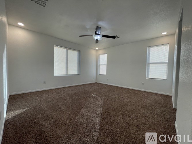 A room with a carpeted floor and a ceiling fan.