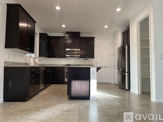 A kitchen with black cabinets and appliances is available for rent.