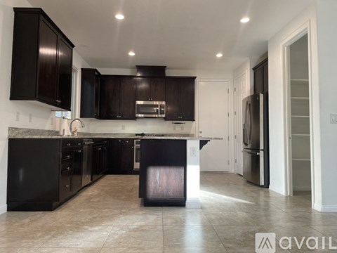 A kitchen with black cabinets and appliances is available for rent.
