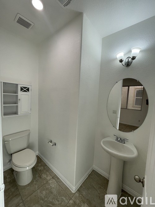 A bathroom with a toilet, sink, and mirror.