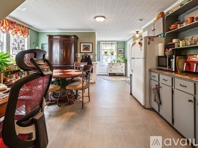 A kitchen with a refrigerator, a dining table with chairs, and a cabinet.
