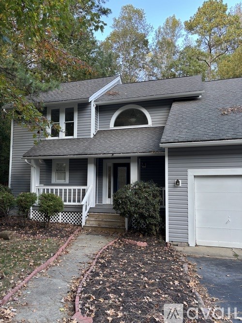 A grey house with a white garage door and a small porch.