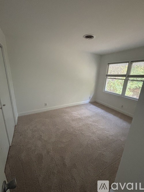 A room with a carpeted floor and a window.