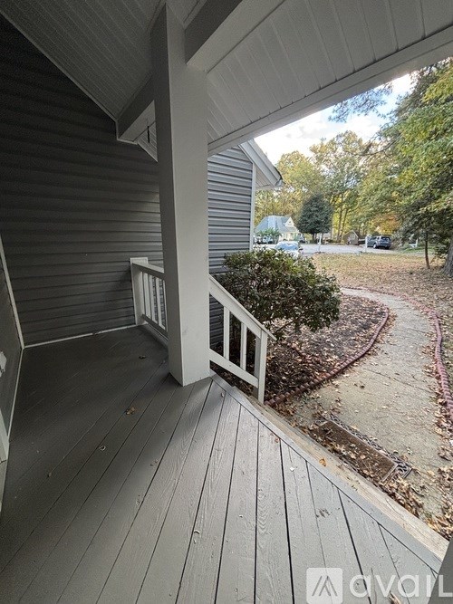 A wooden deck with a railing and a tree-lined pathway.