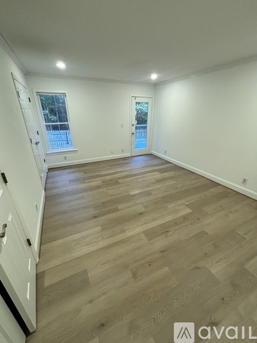 A spacious room with wooden flooring and white walls.