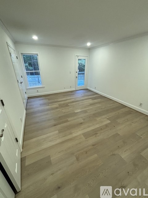 A spacious room with wooden flooring and white walls.