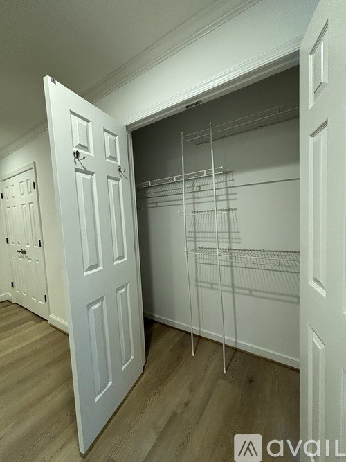 A white closet with a white door and white shelves.