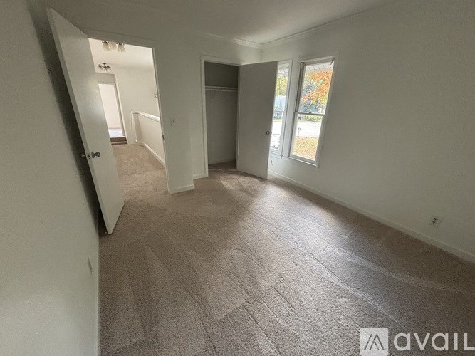 A room with a carpeted floor and a window showing autumn leaves outside.