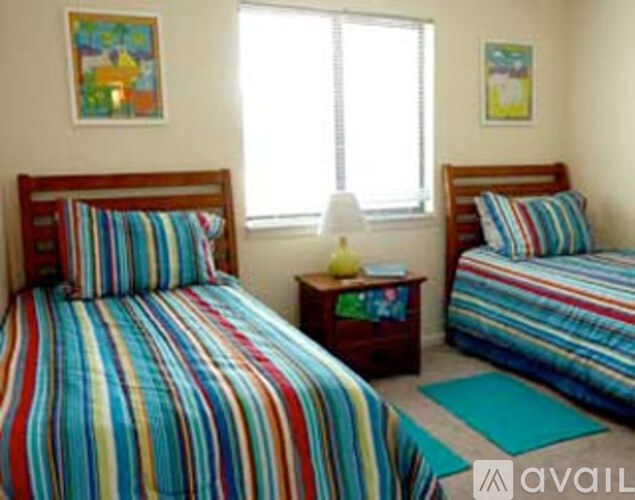 A bedroom with two beds and a nightstand with a lamp.