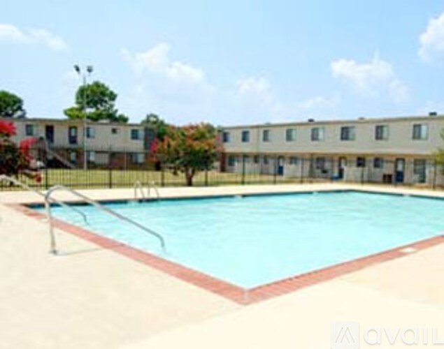 A swimming pool in front of a building with trees.