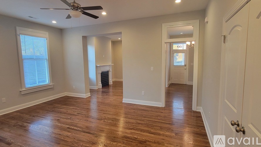 A spacious room with wood flooring and a ceiling fan.
