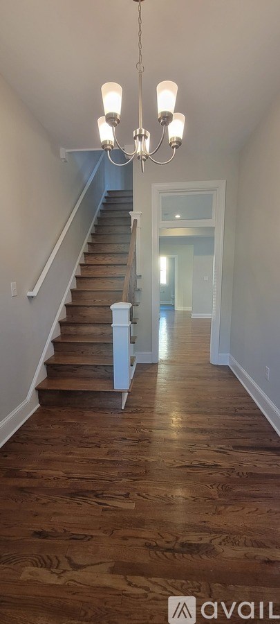 A wooden staircase with a chandelier hanging above it.