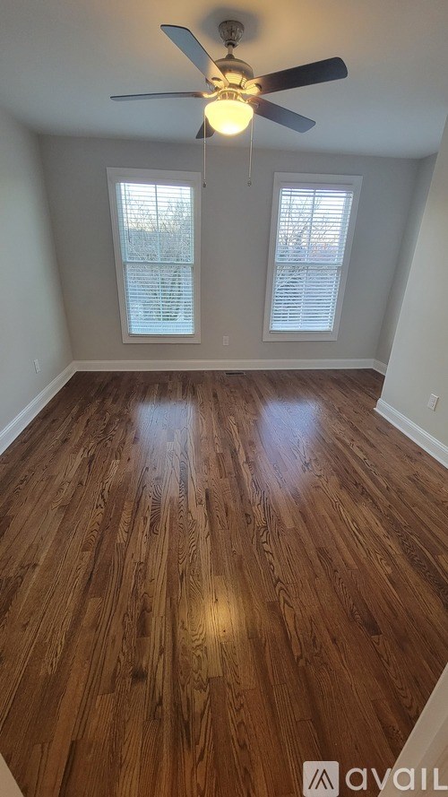 A room with wooden flooring and a ceiling fan.