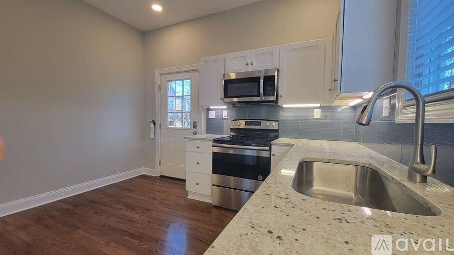 A kitchen with a sink, stove, and microwave.