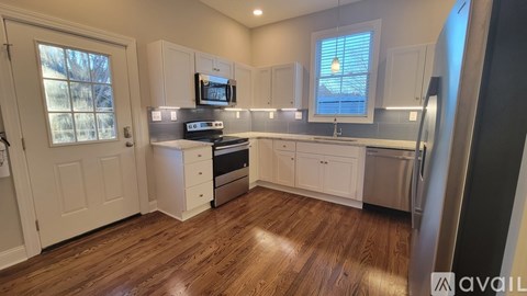 A kitchen with white cabinets and a wooden floor.