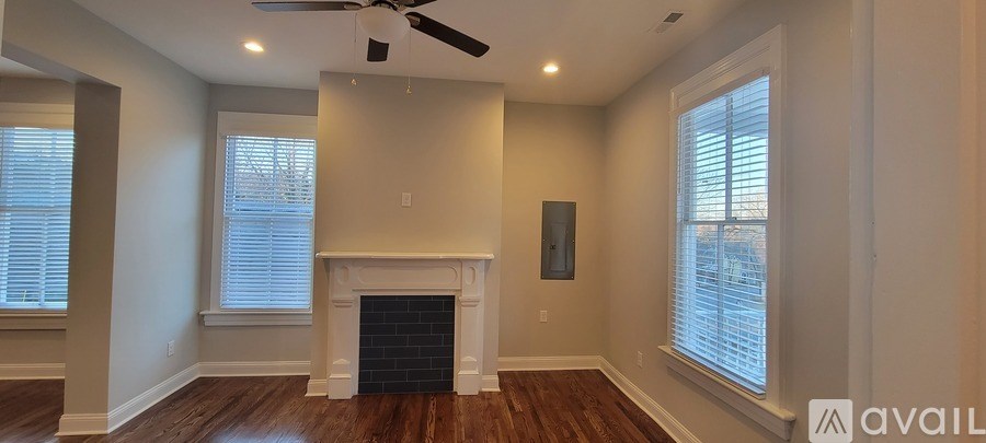 A living room with a fireplace and a ceiling fan.