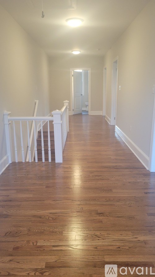 A long hallway with wood floors and white railings.