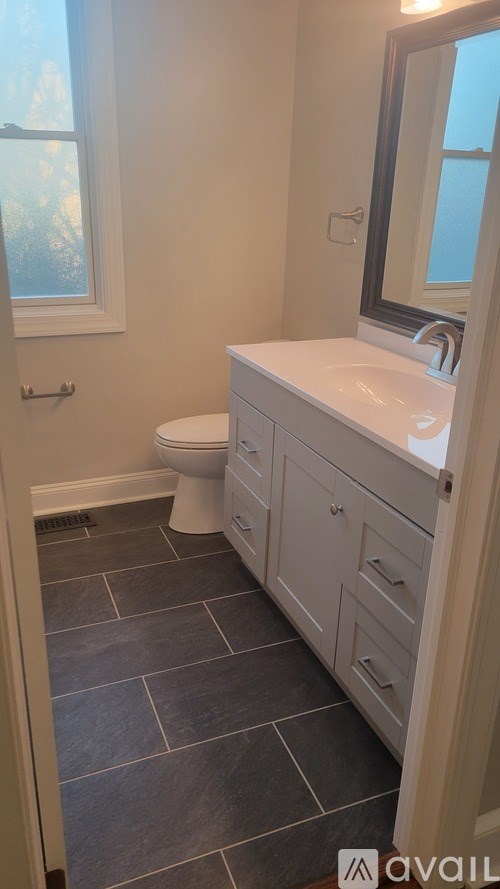 A bathroom with a toilet, sink, and mirror.