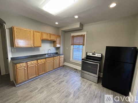 A kitchen with wooden cabinets and a black refrigerator.