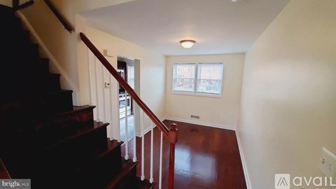A staircase with a wooden handrail and a window with a view of a building.